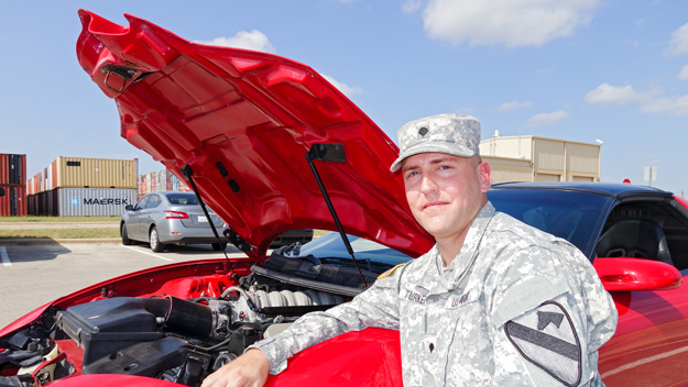 Spc. James Turner kneels by his pride and joy, a souped-up GM Pontiac Trans Am. Turner hopes to keep his family in the Killeen, Texas, community and work at a high-performance, racing garage.  Photo by Pat McKenna/Raytheon